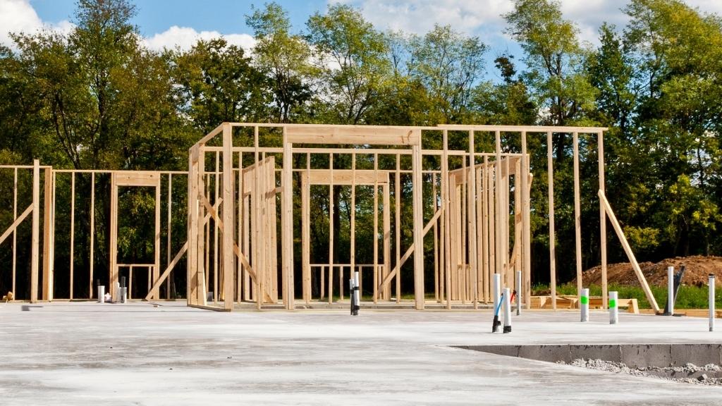 En byggarbetsplats där ett hus börjats byggas på en betongplatta.